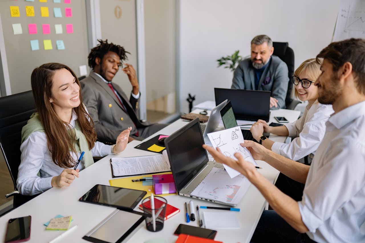 A diverse group of colleagues engaging in a productive office meeting with laptops and notes.